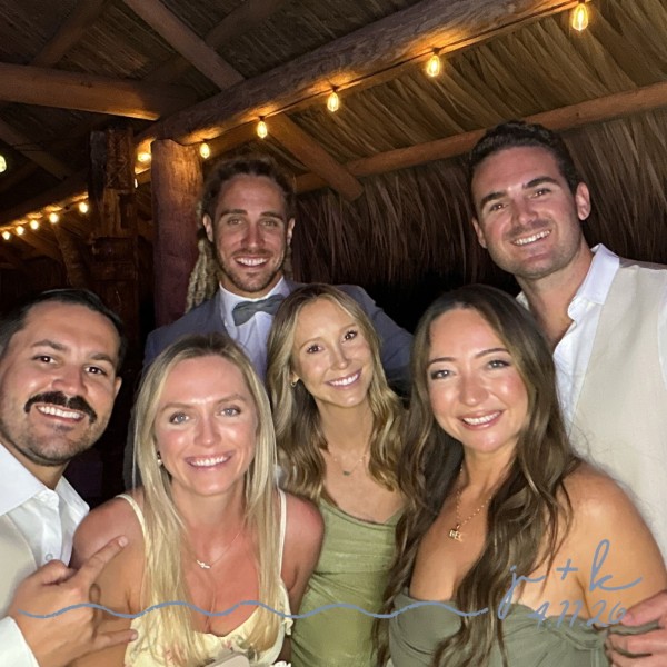 Friends smiling together at a beach wedding